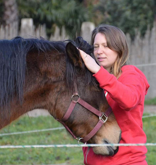 propriétaire de la structure qui caresse un cheval calme, aux yeux fermés